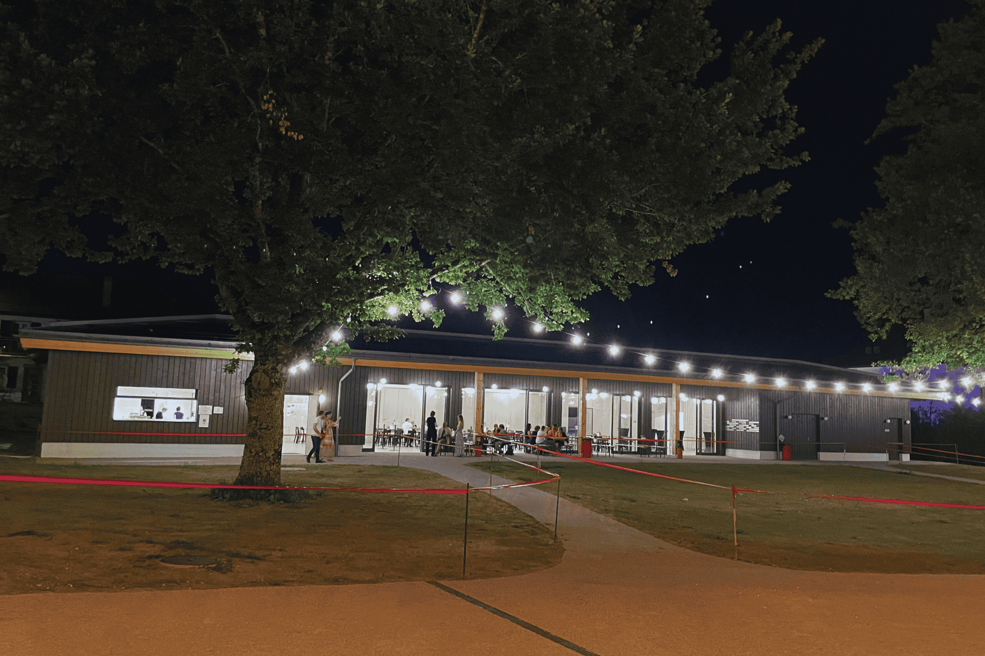 Façade du Pavillon du Théâtre du Jorat de nuit avec jardins et arbres devant.