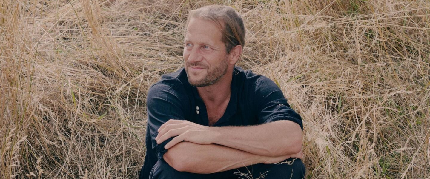 L'auteur Blaise Hofman pose dans un champ pour son spectacle Faire paysan qui parle de nos liens à la terre.